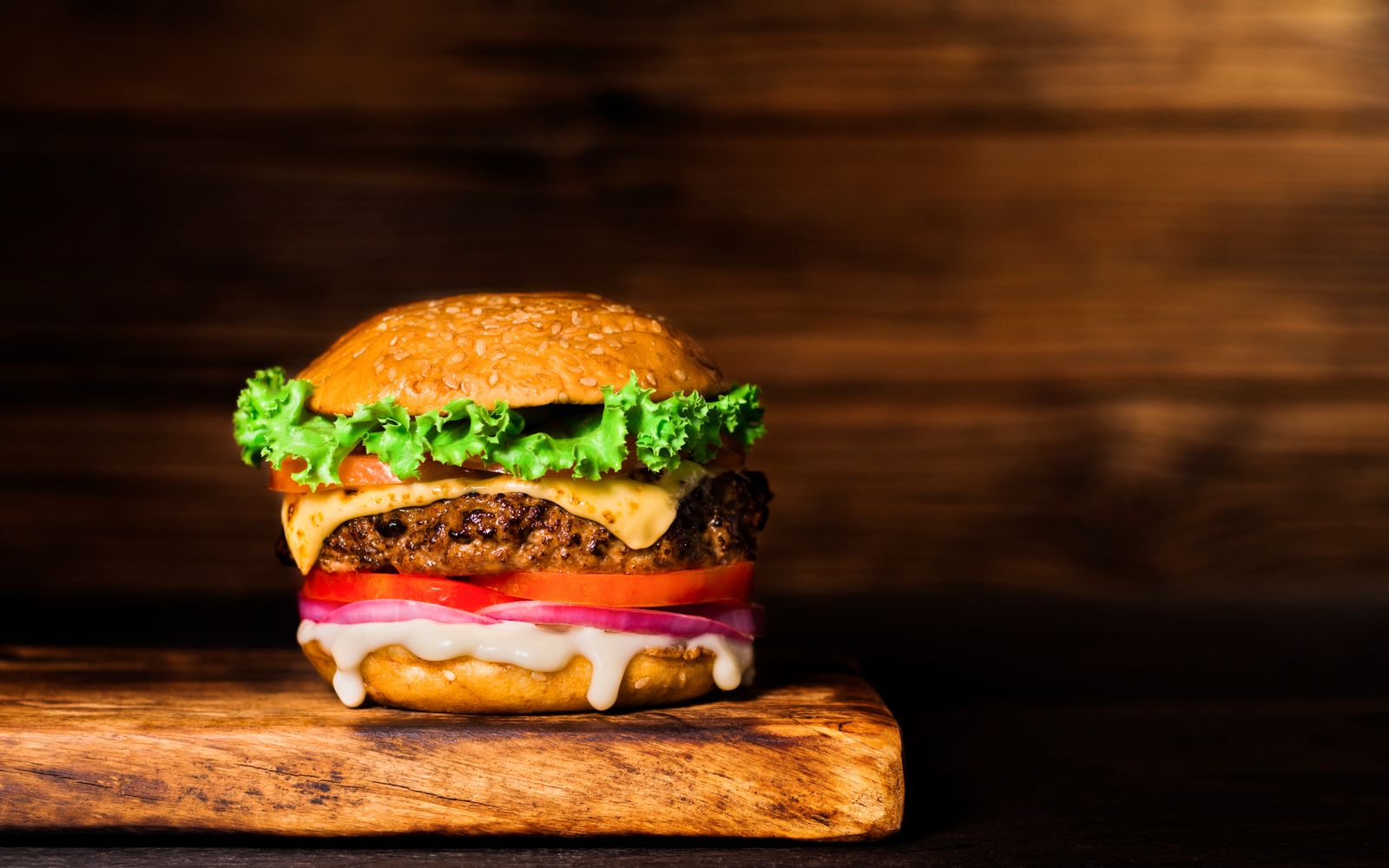 Fresh char-grilled cheeseburger on a wooden board